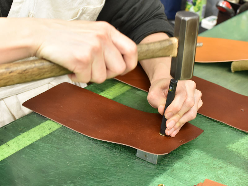 小型の二つ折り財布(WS-64)のホックボタンを取り付ける様子